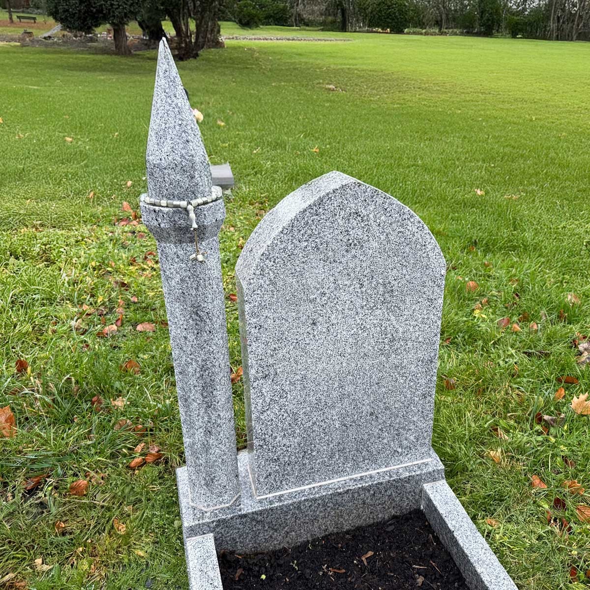 Muslimischer Grabstein Albali: hellgraue Stele mit Spitzbogen und hoher Minarett-Säule an der linken Seite Hauptbild