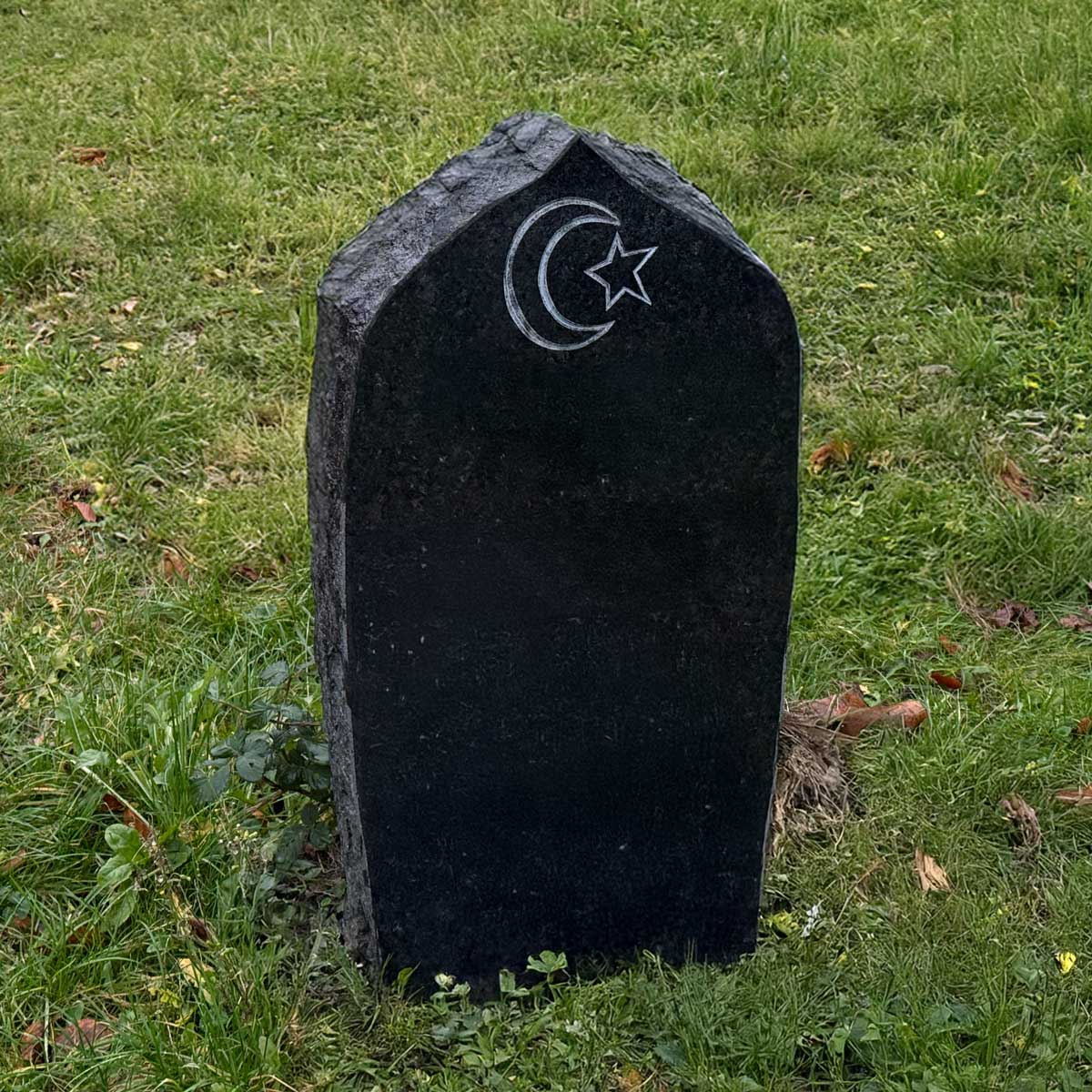 Muslimischer Grabstein Maaz: schwarze Stele mit Spitzgiebel, gehauenen Kanten und graviertem Halbmond mit Stern Hauptbild