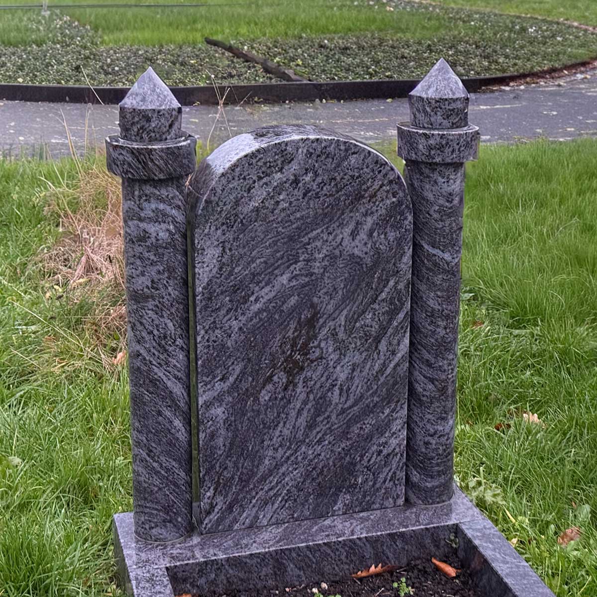 Muslimischer Grabstein Aladfar: blaugraue Stele mit Rundbogen zwischen zwei runden Minarett-Säulen mit Kegelspitze Hauptbild